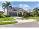 Beautiful single-story home showcasing a well-manicured lawn, a two-car garage, and mature palm trees at 6936 White Willow Ct, Sarasota, FL 34243