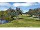 Scenic view of a lush green golf course with mature trees and a tranquil pond on a sunny day at 7602 Partridge Street Cir, Bradenton, FL 34202
