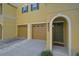 Close-up of a bright yellow townhouse featuring a two-car garage and an arched doorway at 8827 White Sage Loop, Lakewood Ranch, FL 34202