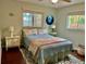 Cozy bedroom with light green walls, wood flooring, and natural light from two windows at 1010 Gun Club Rd, Sarasota, FL 34232