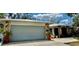 Home featuring large garage door, stone accents and a front patio with seating and potted plants at 1010 Gun Club Rd, Sarasota, FL 34232
