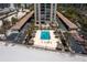 Aerial view of beachfront community pool with sunbathers and lounge chairs in a tropical setting at 1212 Benjamin Franklin Dr # 901, Sarasota, FL 34236