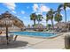 Inviting pool area with tiki huts and lounge chairs surrounded by lush palm trees against a blue sky at 1212 Benjamin Franklin Dr # 901, Sarasota, FL 34236