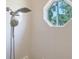Close-up of a white tiled shower area with a handheld shower head and octagonal window at 13625 3Rd Ne Ave, Bradenton, FL 34212