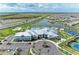 Aerial view of a resort-style community featuring a pool, clubhouse, tennis courts, and lush landscaping by the lake at 15503 Sunny Day Dr, Bradenton, FL 34211