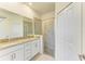 Bathroom featuring double vanity with granite countertop and walk-in shower with glass door at 15503 Sunny Day Dr, Bradenton, FL 34211