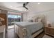 Bright bedroom featuring a large bed, a ceiling fan, and a view of a balcony at 1714 69Th W Ave # C402, Bradenton, FL 34207
