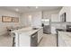 Modern kitchen with stainless steel appliances, white cabinetry, and an island with marble countertops at 17620 Crescent Moon Loop, Bradenton, FL 34211