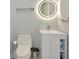 Modern bathroom with a toilet, vanity, and an illuminated mirror showcasing the updated design at 223 Saint James Park, Osprey, FL 34229