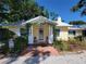 Charming yellow home with a welcoming entrance, featuring a brick walkway and lovely landscaped garden at 230 47Th W St, Bradenton, FL 34209