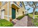 Inviting townhome entrance featuring a green front door, brick walkway, and lush green landscaping at 232 Explorer Dr # 15, Osprey, FL 34229