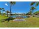 Scenic pond view featuring a swing, palm trees, lush greenery, and clear blue skies at 320 Tropic Dr, Osprey, FL 34229