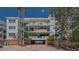Condo building with blue railings, lush landscaping, and brick driveway leads to covered parking area at 340 Gulf Of Mexico Dr # 136, Longboat Key, FL 34228