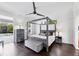 Contemporary bedroom with dark hardwood floors, four-poster bed, and view to the pool area at 3905 Trentwood Pl, Sarasota, FL 34243
