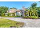 Stately two-story home with a circular driveway, tropical landscaping, and a barrel tile roof at 3905 Trentwood Pl, Sarasota, FL 34243