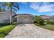 Home with paver driveway leading to a two-car garage, complemented by manicured landscaping and palm trees at 4044 Penshurst Park, Sarasota, FL 34235
