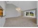 Large living room featuring neutral carpet, modern chandelier, and sliding glass doors to the outside at 4044 Penshurst Park, Sarasota, FL 34235