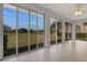Enclosed sunroom with tile floors and expansive sliding glass doors providing panoramic views of the lush green backyard at 4044 Penshurst Park, Sarasota, FL 34235