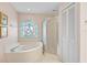 Bright bathroom featuring a soaking tub with a decorative stained glass window and a separate glass-enclosed shower at 4360 Presidential Avenue E Cir, Bradenton, FL 34203