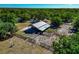 Aerial view of barn featuring a metal roof, stalls, and fenced-in area, surrounded by lush greenery at 4876 253Rd E St, Myakka City, FL 34251