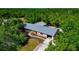 Stunning aerial view of a home featuring a metal roof, driveway, and gorgeous landscaping surrounded by lush greenery at 4876 253Rd E St, Myakka City, FL 34251