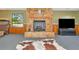 A cozy living room features a stone fireplace, a cowhide rug, and ample natural light at 4876 253Rd E St, Myakka City, FL 34251