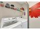 This laundry room includes a washer, a dryer, and a shelf with detergent and supplies at 5448 Crestlake Blvd # 158, Sarasota, FL 34233