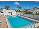 Community pool with a white picket fence surrounded by mature landscaping, palm trees, and clear blue skies at 5448 Crestlake Blvd # 158, Sarasota, FL 34233
