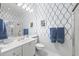 Clean bathroom with white fixtures, shower, a large mirror, and blue and white patterned wallpaper at 5751 Wilena Pl, Sarasota, FL 34238