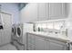 Well-lit laundry room with white cabinetry, sink, and modern washer and dryer at 5751 Wilena Pl, Sarasota, FL 34238