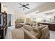 A bright living room with neutral tones, ceiling fan, tile flooring and open access to the kitchen area at 5751 Wilena Pl, Sarasota, FL 34238