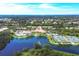 Scenic aerial view of a lake with a fountain, a clubhouse with pools, and tennis courts in the community at 5881 Girona Pl, Sarasota, FL 34238