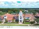 Aerial view of the stunning clubhouse with a clock tower, surrounded by lush landscaping and a serene lake at 5881 Girona Pl, Sarasota, FL 34238