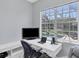 Bright office features a white desk setup and chair with views through the window of the backyard pool at 5881 Girona Pl, Sarasota, FL 34238