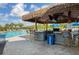 Outdoor pool bar with thatched roof, barstools, and a relaxed atmosphere for poolside refreshments at 5881 Girona Pl, Sarasota, FL 34238