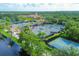 Aerial view of well-maintained tennis courts with sun shelters and lush landscaping near the clubhouse at 5881 Girona Pl, Sarasota, FL 34238