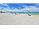 Expansive sandy beach with sunbathers, umbrellas, and calm turquoise water under a partly cloudy sky at 600 Sutton Pl # B305, Longboat Key, FL 34228