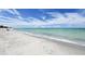 Beautiful sandy beach with gentle waves meeting the shore under a partly cloudy blue sky, offering a serene view at 600 Sutton Pl # B305, Longboat Key, FL 34228
