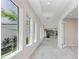 Bright hallway featuring tray ceilings, natural light, and views of the kitchen. Light wood-look tile flooring throughout at 6028 Cat Claw Ln, Bradenton, FL 34210
