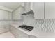Well-lit kitchen showcasing gray cabinets, mosaic backsplash, a stainless steel range hood, and a gas cooktop at 6028 Cat Claw Ln, Bradenton, FL 34210