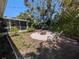 Backyard featuring a fire pit, chairs, landscaping, and screened-in patio at 609 Glen Oak Rd, Venice, FL 34293
