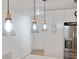 Kitchen features modern pendant lighting, stainless refrigerator, and white cabinetry at 609 Glen Oak Rd, Venice, FL 34293