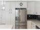 Modern kitchen with stainless steel refrigerator, white cabinets, hexagon backsplash, and clean countertops at 609 Glen Oak Rd, Venice, FL 34293