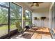 Charming screened-in porch with wood-look floors, two chairs, a table, fan and views of green landscaping at 6124 35Th E Ct, Bradenton, FL 34203