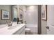 Bright bathroom with white vanity, framed artwork, framed mirror, framed shower curtain and a tub shower combo at 6908 Prairie Oak Way, Nokomis, FL 34275