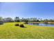 Expansive backyard featuring lush green lawn, mature trees, and a tranquil pond at 7034 Honeysuckle Trl, Lakewood Ranch, FL 34202