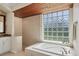 Bright bathroom featuring a large soaking tub, glass block window, and tiled shower at 7034 Honeysuckle Trl, Lakewood Ranch, FL 34202