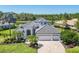 Charming home featuring a well-manicured lawn, lush landscaping, and a picturesque pond in the background at 7034 Honeysuckle Trl, Lakewood Ranch, FL 34202