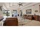 Elegant living room featuring a ceiling fan, modern fireplace and entertainment center, and stylish leather furniture at 7034 Honeysuckle Trl, Lakewood Ranch, FL 34202