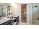 Modern bathroom boasts double sinks, quartz countertops, glass shower, and walk-in closet at 7052 Foxboro Way, Nokomis, FL 34275